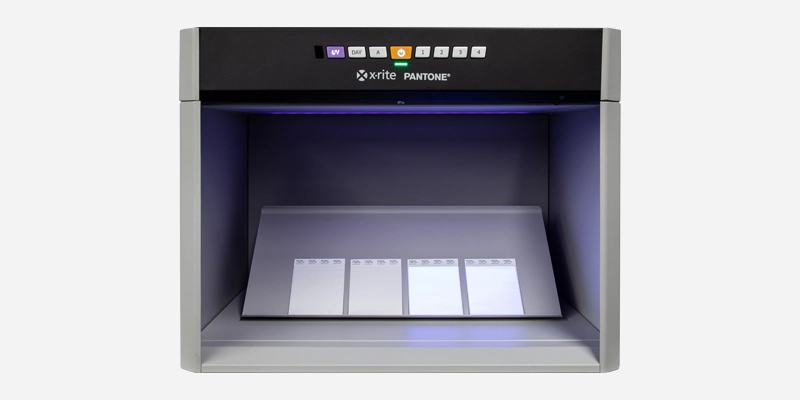 Cloud Dancer color samples displayed under daylight and UV in a light booth to highlight how OBAs affect the appearance of the PANTONE Color of the Year 2026 in packaging applications.