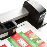 eXact Auto-Scan automated color scanning device capturing spectral data from a press sheet as part of closed-loop color control for offset printing.